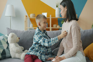 Female clinician holding stethoscope on young girls chest